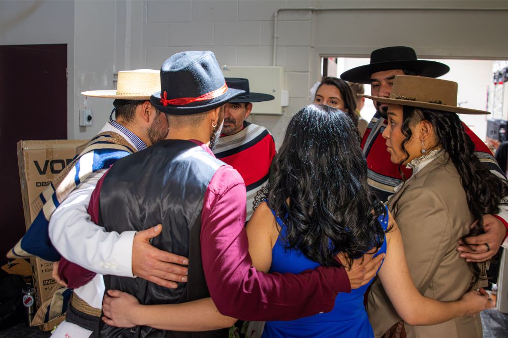 Performers embracing backstage before a cultural performance at the Latin American Spring Festival
